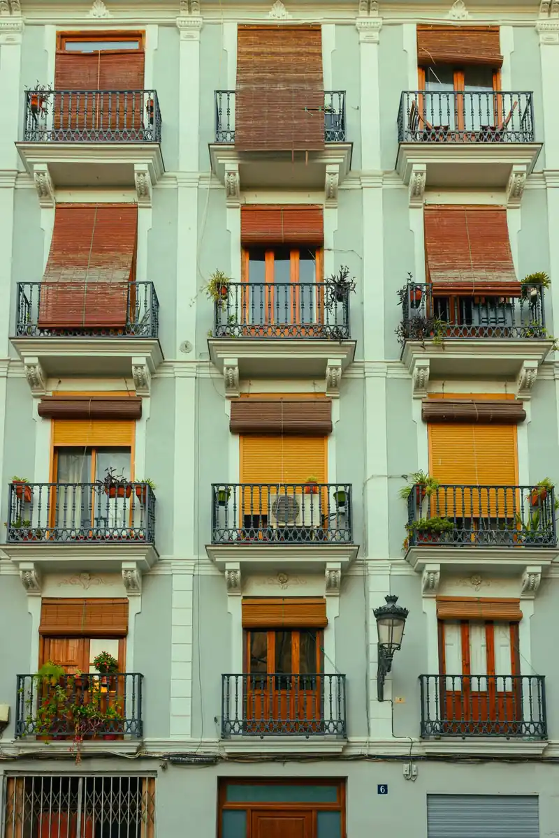 Traditional apartment building in Valencia with iron balconies, wooden blinds and potted plants